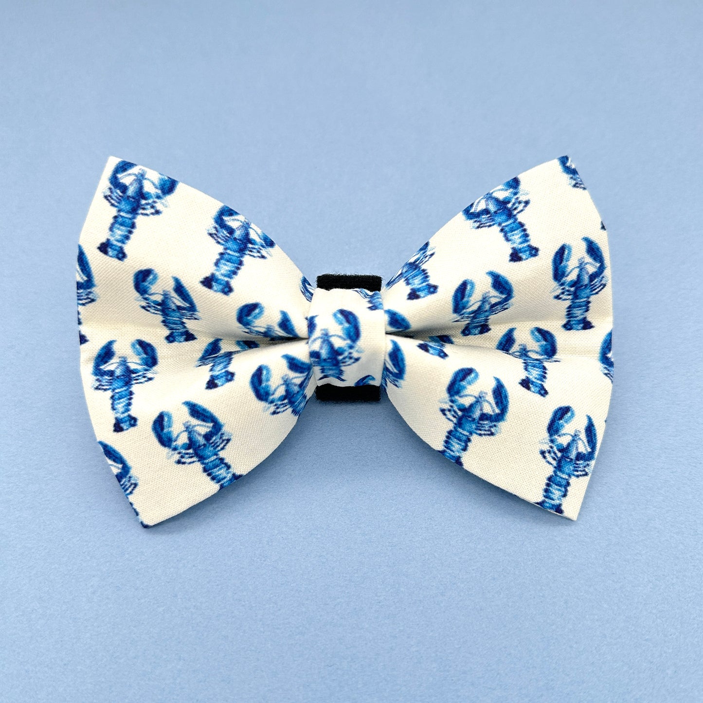 White bow tie with blue lobster pattern on a light blue background