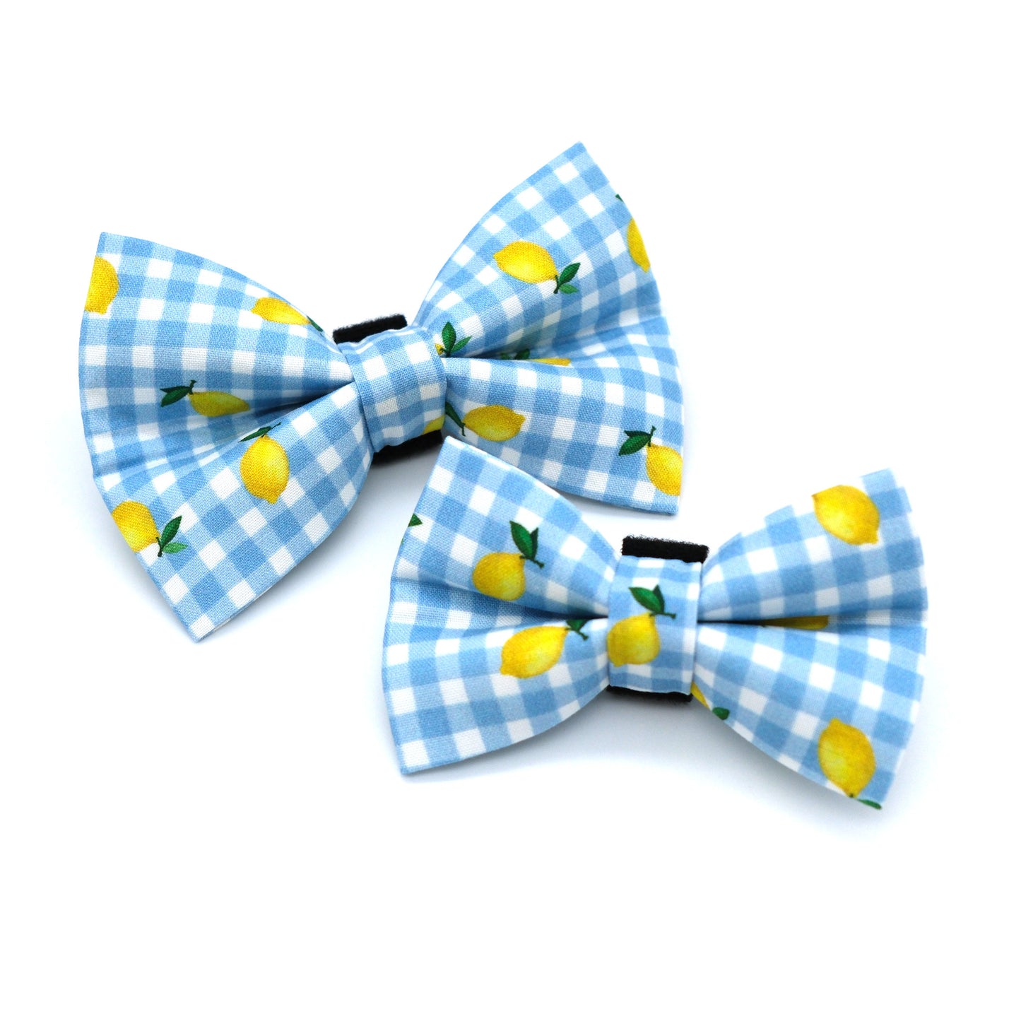 Two matching fabric bow ties with a light blue and white gingham pattern and yellow lemon prints, displayed on a clean white background.